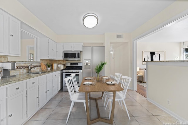 kitchen with backsplash, white cabinets, sink, light stone counters, and stainless steel appliances