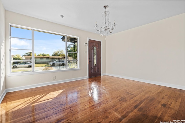 spare room with hardwood / wood-style flooring and a notable chandelier