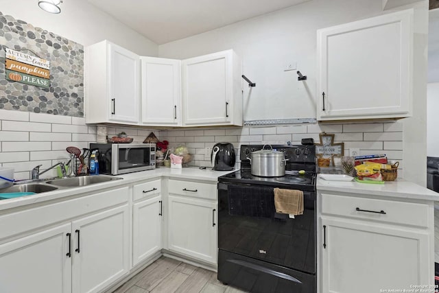 kitchen featuring white cabinetry, sink, and black range with electric cooktop