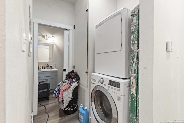 laundry area featuring hardwood / wood-style floors and stacked washer and clothes dryer