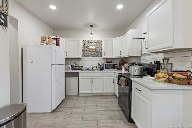 kitchen with black / electric stove, tasteful backsplash, white cabinets, white fridge, and hanging light fixtures