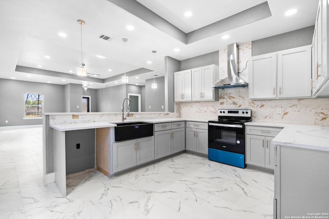 kitchen with electric range, wall chimney exhaust hood, gray cabinets, and a tray ceiling