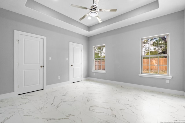 empty room with a tray ceiling and ceiling fan