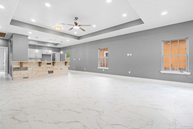 unfurnished living room with a tray ceiling and ceiling fan