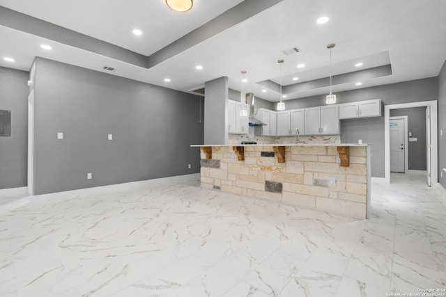 kitchen with decorative light fixtures, a kitchen island, and a tray ceiling