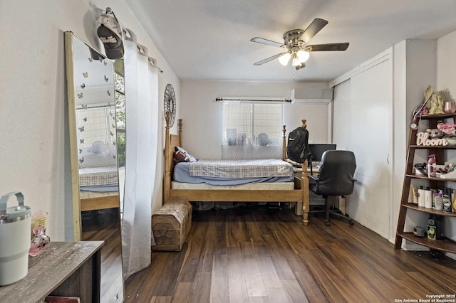 bedroom with dark hardwood / wood-style floors, an AC wall unit, and ceiling fan