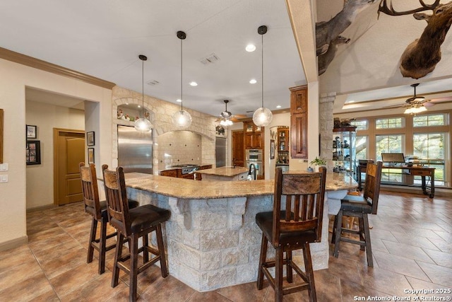 kitchen with pendant lighting, light stone counters, a kitchen bar, kitchen peninsula, and stainless steel appliances