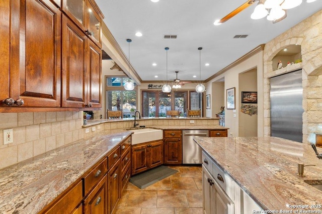 kitchen featuring light stone countertops, tasteful backsplash, stainless steel appliances, sink, and pendant lighting