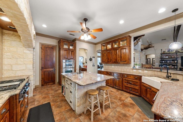 kitchen with sink, light stone counters, a kitchen bar, a kitchen island, and appliances with stainless steel finishes