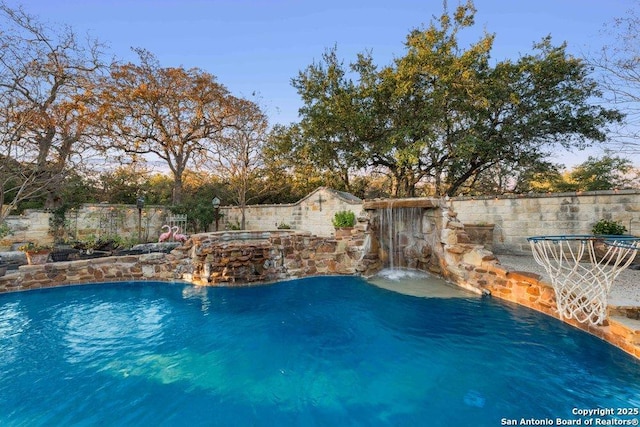 view of pool with pool water feature and a hot tub