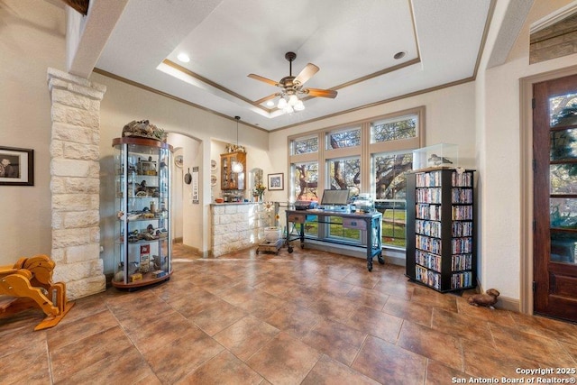 living area with a tray ceiling, ceiling fan, and ornamental molding