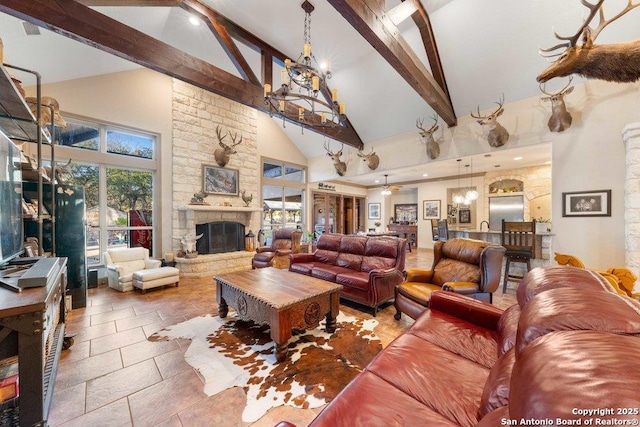 living room featuring ceiling fan with notable chandelier, beam ceiling, a fireplace, and high vaulted ceiling