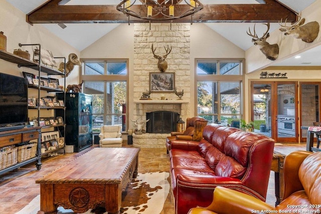 living room featuring a stone fireplace, french doors, beamed ceiling, and a healthy amount of sunlight