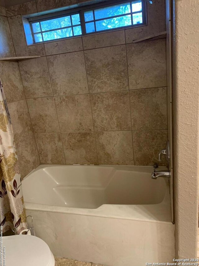 bathroom featuring shower / tub combo and toilet