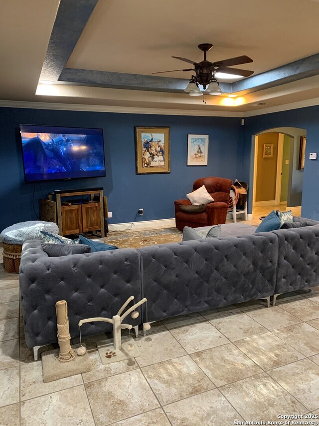 tiled cinema featuring a tray ceiling, ceiling fan, and crown molding