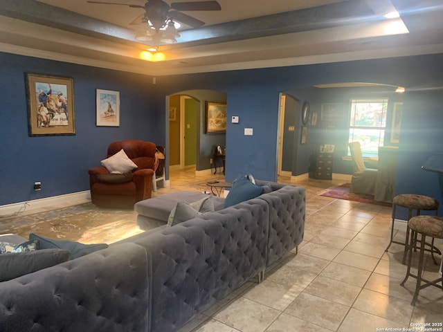 living room with ceiling fan, light tile patterned floors, and a tray ceiling