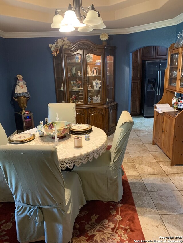 tiled dining space with a tray ceiling, a notable chandelier, and ornamental molding