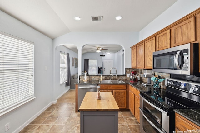 kitchen with stainless steel appliances, ceiling fan, sink, a center island, and butcher block counters