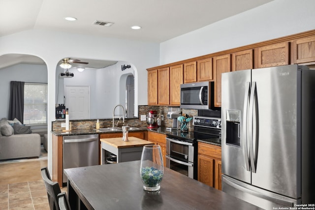 kitchen featuring sink, vaulted ceiling, ceiling fan, tasteful backsplash, and stainless steel appliances