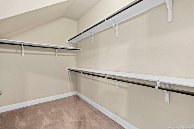 walk in closet featuring light colored carpet and vaulted ceiling