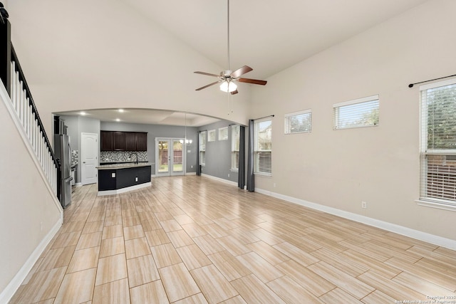 unfurnished living room featuring high vaulted ceiling, ceiling fan, and sink