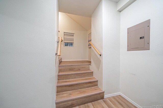 stairs with hardwood / wood-style floors and electric panel