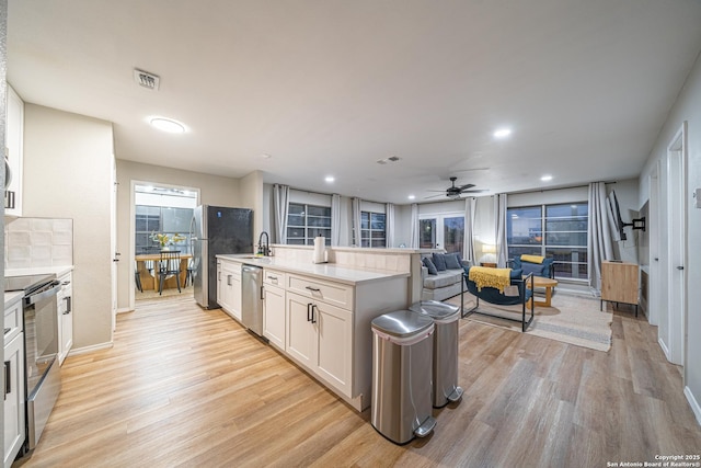 kitchen with white cabinets, stainless steel appliances, light hardwood / wood-style flooring, and ceiling fan