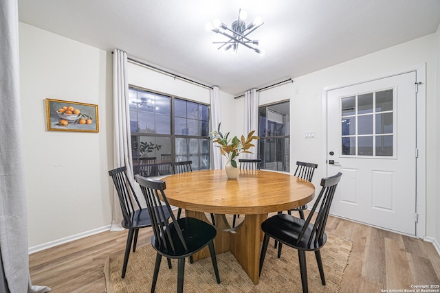 dining space with light hardwood / wood-style floors and an inviting chandelier