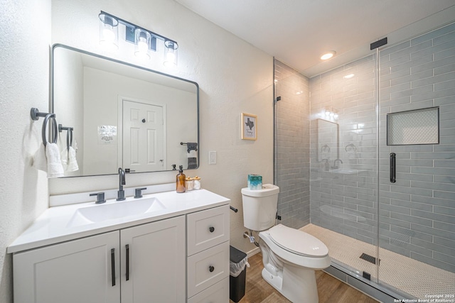 bathroom featuring hardwood / wood-style floors, vanity, toilet, and a shower with door