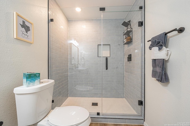 bathroom with toilet and a shower with shower door