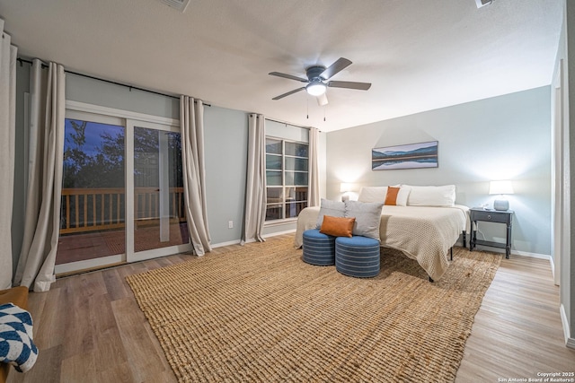 bedroom with access to exterior, hardwood / wood-style floors, and ceiling fan