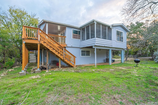 rear view of house featuring a sunroom, central AC unit, a deck, and a lawn