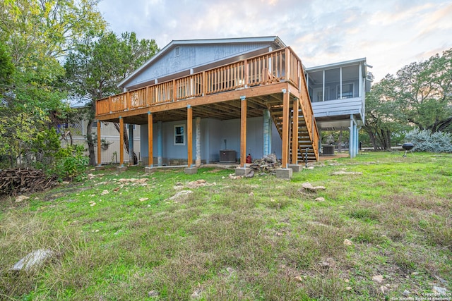 back of house with central AC, a deck, a lawn, and a sunroom