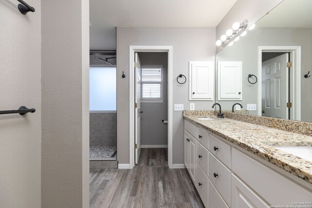 bathroom with vanity, wood-type flooring, and tiled shower