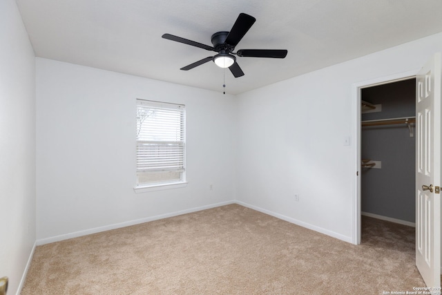 unfurnished bedroom with a spacious closet, a closet, ceiling fan, and light colored carpet