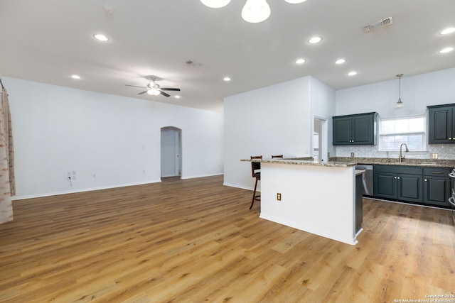 kitchen featuring ceiling fan, light hardwood / wood-style floors, tasteful backsplash, decorative light fixtures, and a kitchen island