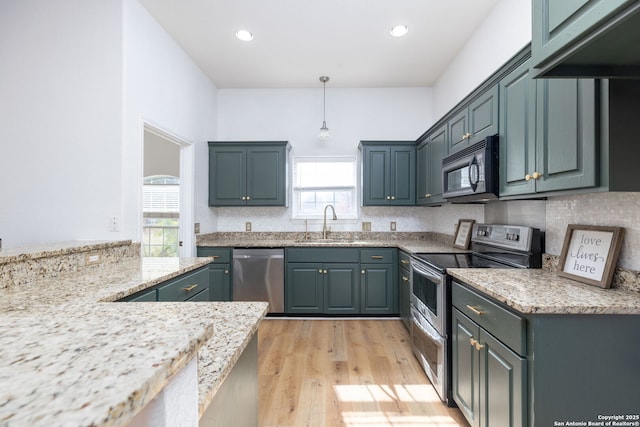 kitchen with sink, light wood-type flooring, light stone countertops, appliances with stainless steel finishes, and decorative light fixtures