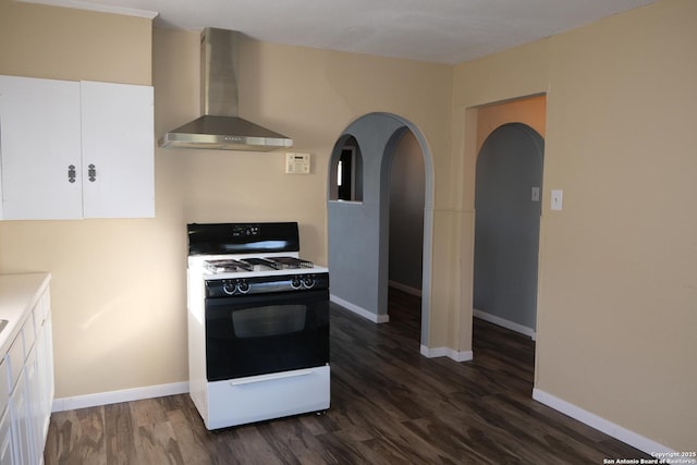 kitchen featuring white cabinets, white gas range oven, dark hardwood / wood-style floors, and wall chimney exhaust hood