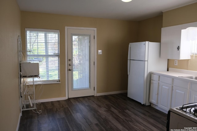 kitchen featuring stove, dark wood-type flooring, sink, white refrigerator, and white cabinets