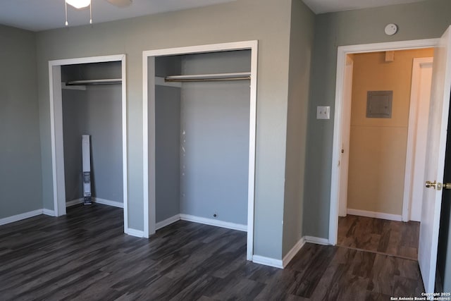 unfurnished bedroom featuring two closets, electric panel, and dark hardwood / wood-style floors