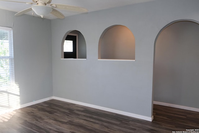 unfurnished room featuring ceiling fan, a healthy amount of sunlight, and dark hardwood / wood-style floors