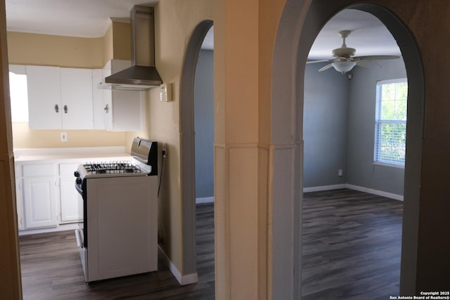 kitchen with white cabinets, dark hardwood / wood-style flooring, range, and wall chimney range hood