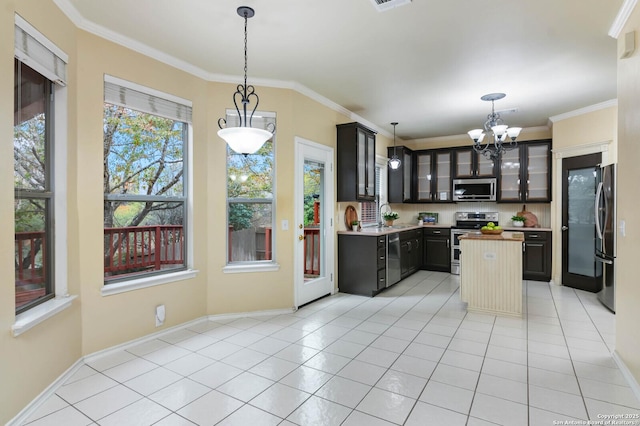 kitchen with appliances with stainless steel finishes, ornamental molding, sink, pendant lighting, and light tile patterned flooring