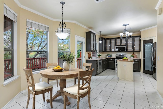 dining room featuring sink, light tile patterned floors, a chandelier, and ornamental molding