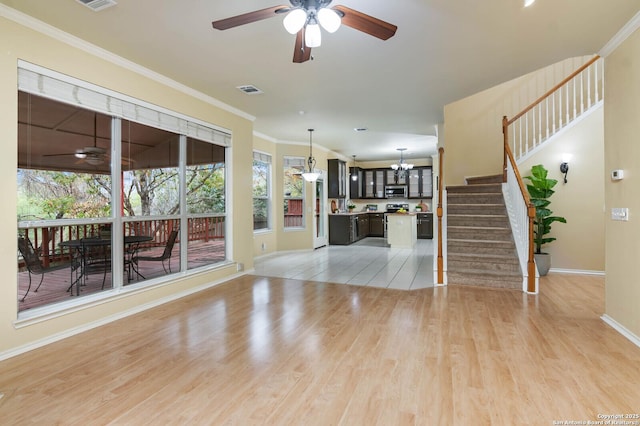 living room with ceiling fan with notable chandelier, light wood-type flooring, and crown molding