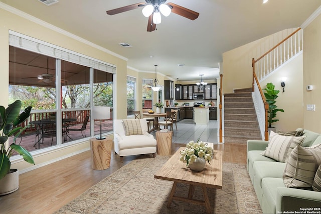 living room featuring hardwood / wood-style floors, ceiling fan with notable chandelier, and ornamental molding