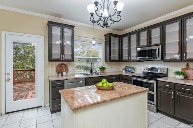 kitchen featuring sink, appliances with stainless steel finishes, pendant lighting, a kitchen island, and ornamental molding