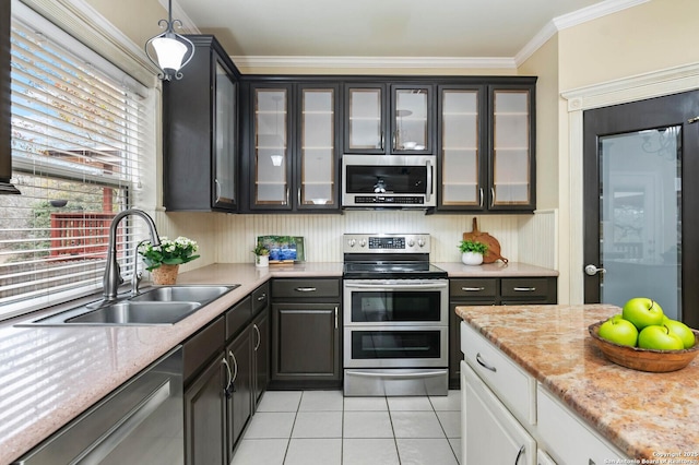 kitchen featuring white cabinets, sink, hanging light fixtures, light tile patterned floors, and stainless steel appliances