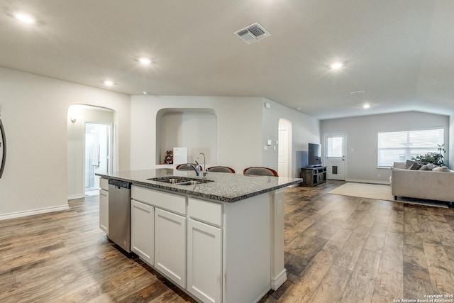 kitchen with sink, stone countertops, dishwasher, white cabinetry, and an island with sink