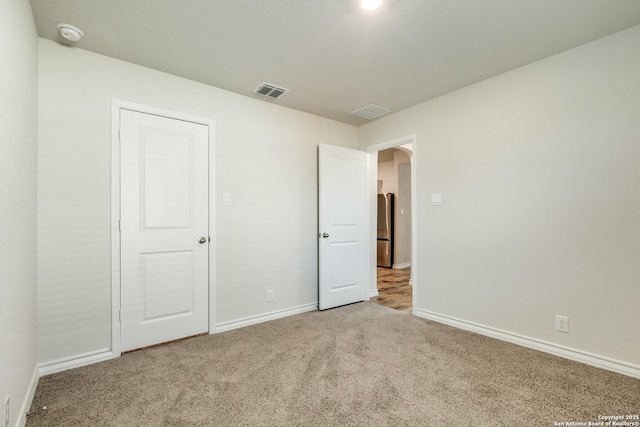 unfurnished bedroom with carpet and stainless steel fridge